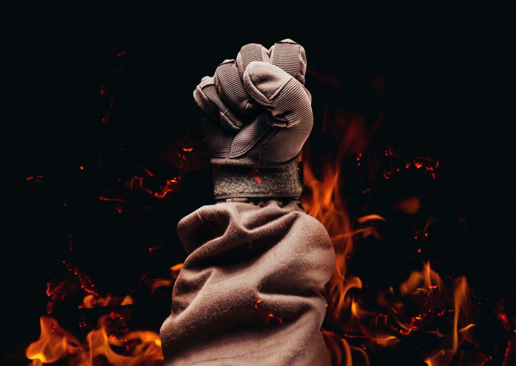 A gloved hand ablaze, protected by Flame Resistant Clothing, showcases the importance of fire safety.